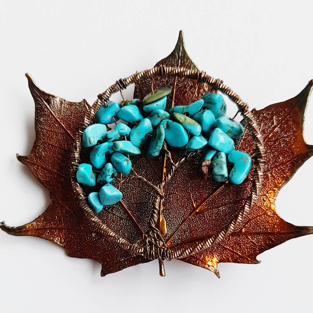 Metal sculpture of maple leaf with polished stones and metal ring